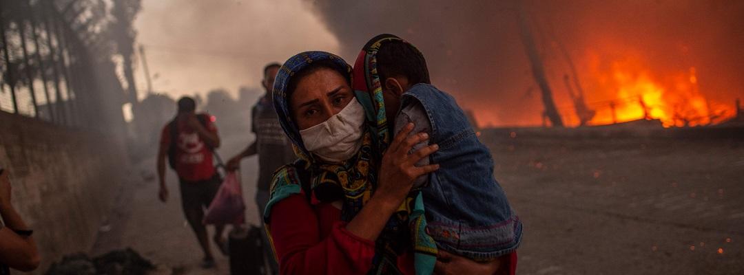 En mor flygter fra brand i Moria med sit barn.