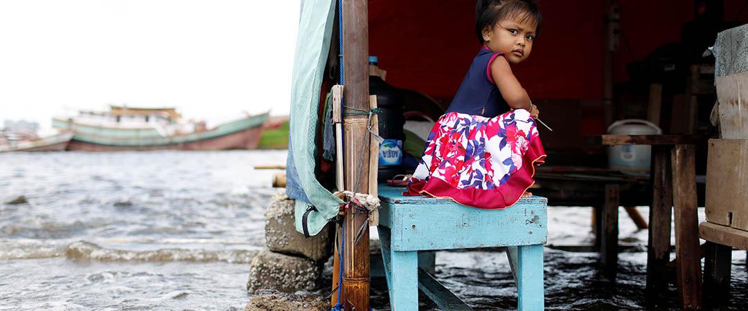 Pige sidder på en bænk i hendes oversvømmede hjem.