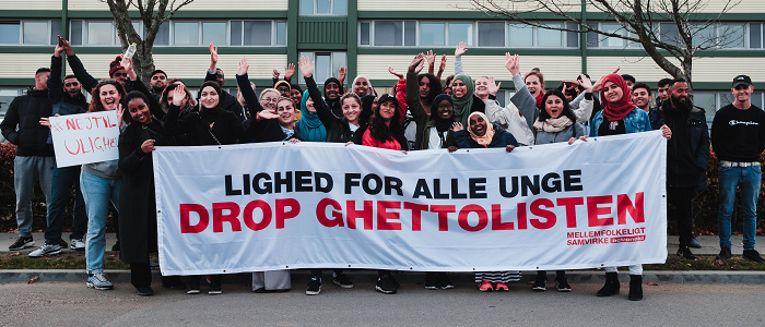 Gruppe står foran "drop ghettolisten" banner